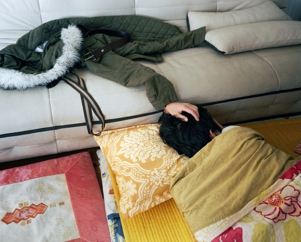 Manteau sur un canapé dont la manche semble être le bras d'une personne allongée